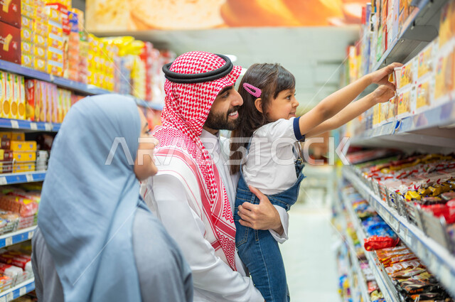 مساعدة وتعليم الأبناء الشراء من الماركت، التعاون في شراء السلع والمواد الغذائيه المختلفة في السوبرماركت، زوجان عربيان خليجيان سعوديان يقومان بقضاء أوقات ممتعة بالتسوق واختيار اللوازم المنزليه برفقه ابنتهم، التمتع بالتخفيضات والعروض والخصومات على المنتجات.