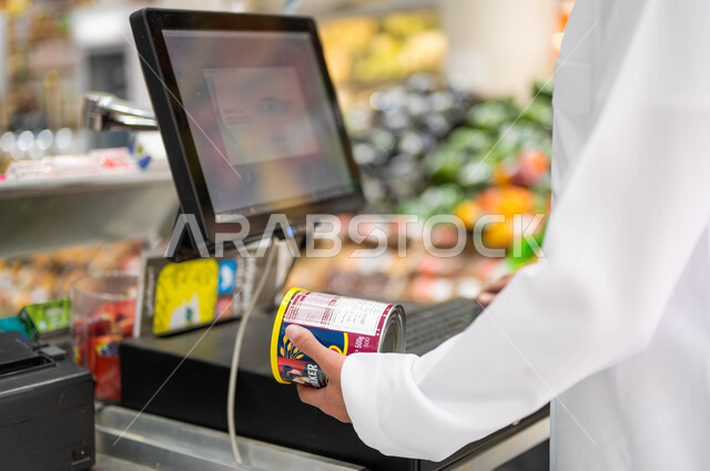 الدقة في العمل ومعرفة أسعار البضائع الجديدة، صوره مقربة لأمين صندوق عربي خليجي سعودي يقوم بتسجيل وإدخال سعر المنتج من خلال أنظمة الحاسب المتطوره، محاسبة الزبائن على المشتريات، منتجات محليه وطنيه في السعوديه، تنزيلات وحسومات الجمعة البيضاء.