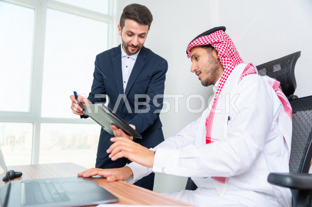 رجل اعمال سعودي خليجي يجلس في مكتبه  ، بجانبه السكرتير الخاص فيه يديرالمهام اليومية ،ادارة الاعمال داخل مقر الشركة ، شركة سعودية ، بيئة العمل