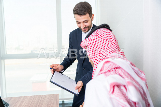 رجل اعمال سعودي خليجي يجلس في مكتبه  ، بجانبه السكرتير الخاص فيه يديرالمهام اليومية ،ادارة الاعمال داخل مقر الشركة ، شركة سعودية ، بيئة العمل