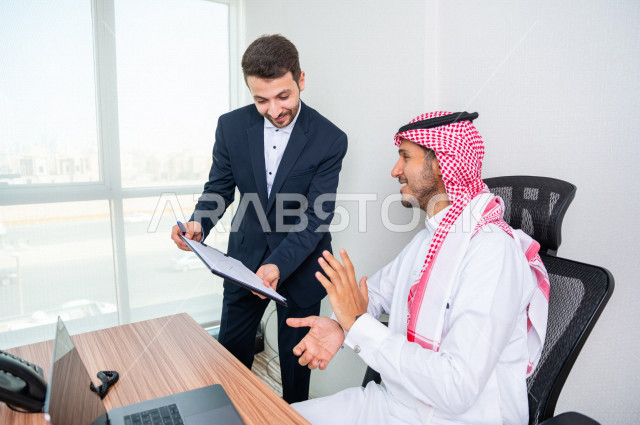 A Saudi Gulf businessman sits in his office, next to him his private secretary manages the daily tasks, running the business inside the company's headquarters, a Saudi company, the work environment