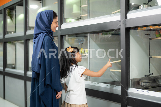 قضاء وقت ممتع ومسلي في مشاهدة الطيور، غرف زجاجية خاصة لحفظ العصافير، أم عربية خليجية سعودية محجبة ترتدي العباءة الخليجية تقوم بزيارة محلات ومتاجر بيع وشراء الحيوانات والطيور الأليفة برفقة ابنتها الصغيرة، الشغف بتربية الحيوانات الاليفة في المنزل