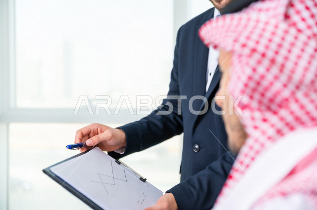 رجل اعمال سعودي خليجي يجلس في مكتبه  ، بجانبه السكرتير الخاص فيه يديرالمهام اليومية ،ادارة الاعمال داخل مقر الشركة ، شركة سعودية ، بيئة العمل