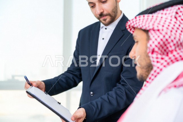 رجل اعمال سعودي خليجي يجلس في مكتبه  ، بجانبه السكرتير الخاص فيه يديرالمهام اليومية ،ادارة الاعمال داخل مقر الشركة ، شركة سعودية ، بيئة العمل