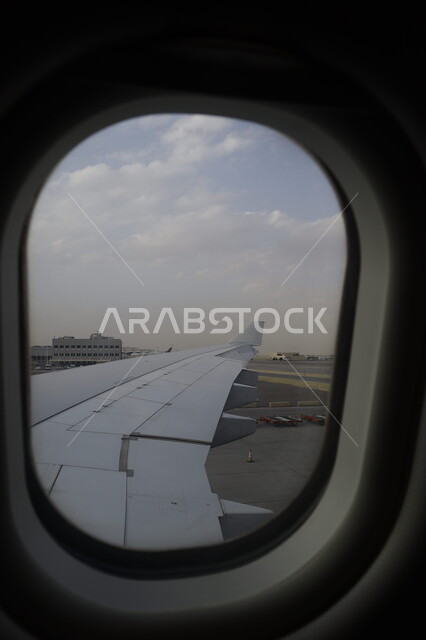 View of clouds in the sky, close-up of the plane window of an airplane wing at the airport, airlines and airlines in the Kingdom of Saudi Arabia, air transportation, tourist flights.
