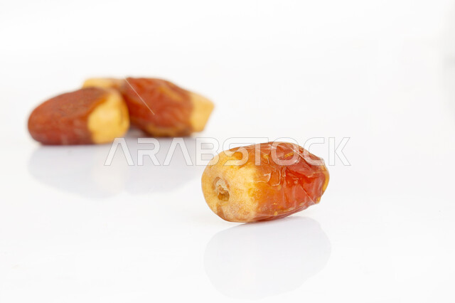 حبات من تمر الصقعي الناضج والصحي، أنواع التمور في المملكة العربية السعودية، ثمار أشجار النخيل الناضجة، وجبة ذات قيمة غذائية عالية، الضيافة الرمضانية، خلفية بيضاء