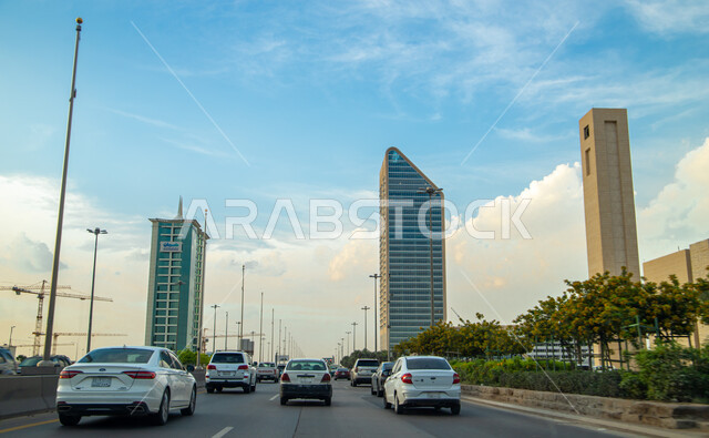 الفن الهندسي المعماري في الأبراج وناطحات السحاب، السحب البيضاء الكثيفة في سماء المملكة العربية السعودية، حركة سير السيارات في طريق الملك فهد في الرياض، أماكن ومعالم سياحية مشهورة في مدينة الرياض في وضح النهار، تطوير التصميمات الهندسية للمباني 