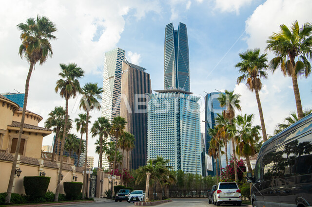 أشجار النخيل الخضراء في مدخل مركز الملك عبدالله المالي (كافد) في الرياض بالمملكة العربية السعودية، أماكن ومعالم سياحية مشهورة بالرياض، منظر السحب الكثيفة في السماء في وضح النهار، المنافسة في التصاميم الفنية الهندسية المختلفة للأبراج وناطحات السحاب