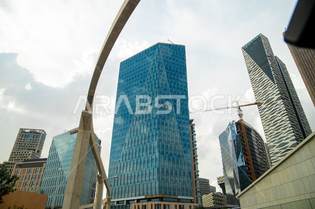 الاستمرار في تطوير وتحديث التصاميم الهندسية  للمباني، صورة من الاسفل لأبراج مركز الملك عبدالله المالي (كافد) في الرياض بالمملكة العربية السعودية، أماكن ومعالم سياحية مشهورة بالرياض، منظر السحب الكثيفة في السماء في وضح النهار
