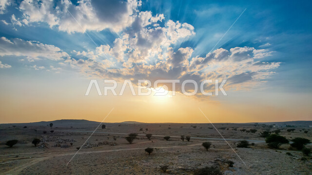 منظر السماء والسحب في سماء المملكة العربية السعودية وقت غروب الشمس فوق الصحراء في مدينة الرياض، البيئة الصحراوية والنباتات والأشجار الخضراء في الأراضي الجافة، أماكن لرحلات السفاري في السعوديه، مناطق سياحية ترفيهية مشهورة