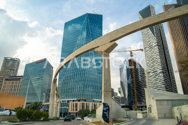 مدخل مركز الملك عبدالله المالي (كافد) في الرياض بالمملكة العربية السعودية، أماكن ومعالم سياحية مشهورة بالرياض، منظر السحب الكثيفة في السماء في وضح النهار، المنافسة و الاستمرار في تطوير و تحديث التصاميم الهندسية  للمباني والأبراج