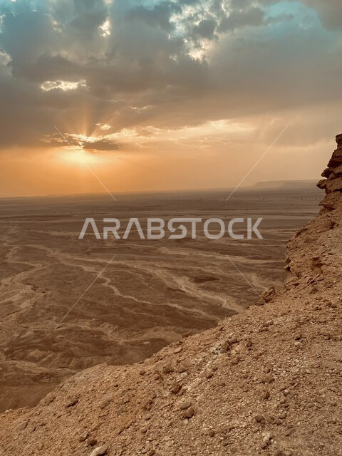 صورة مقربة للقم والمرتفعات والجبال الصخرية في الصحراء، السماء المغطاة بالغيوم والسحب وقت غروب الشمس، الطبيعة الجبلية والتضاريس الصحراوية الطبيعية
