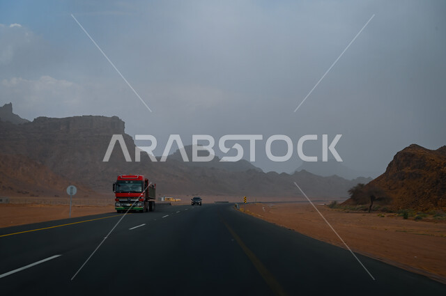 خدمة نقل البضائع على الطرق السريعة, شاحنة على طريق اسفلتي في المملكة العربية السعودية, الجبال و الطبيعة الصحراوية الجبلية و التشكيلات الصخرية في محافظة العلا, المرتفعات الصخريه على جوانب الطرقات المعبده في مدينة العلا