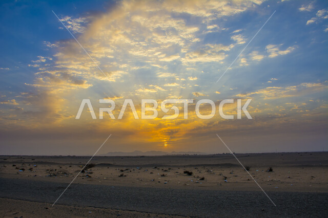 النباتات البريه و الشروق فوق البيئه الصحراويه, غياب ضوء الشمس خلف السحب البيضاء ,منظر تداخل الغيوم مع أشعة الشمس في سماء السعودية, الرمال والكثبان الرملية في الصحراء وقت الغروب