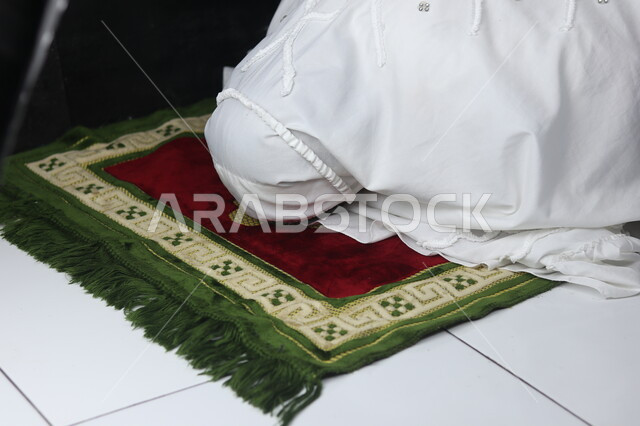 الطاعة والعبادة والتقرب إلى الله عن طريق القيام بالفرائض والعبادات، صورة مقربة لإمرأة عربية خليجية سعودية ترتدي ملابس الصلاة البيضاء تقوم بأداء الفرائض، التضرع والخشوع أثناء السجود، إصلاح النفس بالتذلل لرب العالمين