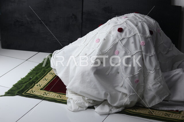 التضرع والخشوع أثناء السجود، الطاعة والعبادة والتقرب إلى الله عن طريق القيام بالفرائض والعبادات، إمرأة عربية خليجية سعودية ترتدي ملابس الصلاة البيضاء تقوم بأداء الفرائض، إصلاح النفس بالتذلل لرب العالمين