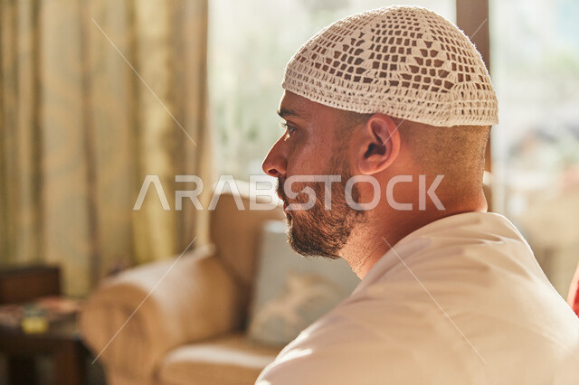 اتخاذ القرارات و حل المشكلات، صورة جانبية مقربة لرجل عربي خليجي اماراتي يرتدي الكندورة والطاقية الاماراتية البيضاء يقوم بالتفكير والتخطيط للمستقبل، ايماءات الاندماج و شرود الذهن، النظر إلى شيء ما.