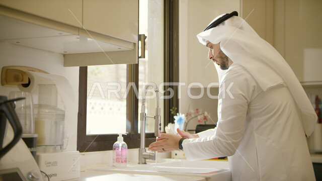 اتباع أساليب الحرص وتجنب انتشار العدوى، مفهوم العناية بنظافة اليدين, رجل عربي خليجي إماراتي يرتدي الكندورة والغترة يقوم بغسل يديه، ضرورة الالتزام بتعاليم النظافة الشخصية في زمن الكورونا