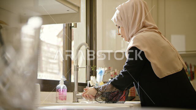 مفهوم العناية بنظافة اليدين, صورة مقربة لسيدة عربية خليجية إماراتية محجبة تقوم بغسل يديها, ضرورة الالتزام بتعاليم النظافة الشخصية في زمن الكورونا, اتباع أساليب الحرص وتجنب انتشار العدوى