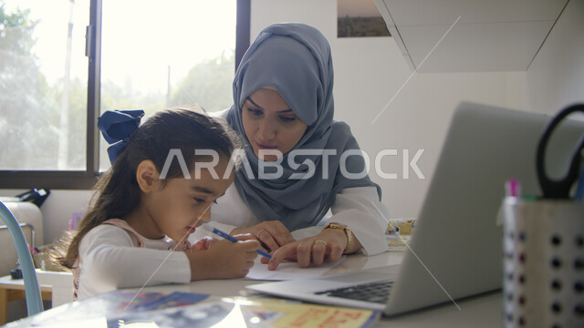 متابعة الدروس والواجبات عبر الانترنت ومساعدة الأبناء, مفهوم التعليم الالكتروني والبحث عن معلومة ما عبر الأونلاين, تلميذة عربية خليجية إماراتية تجلس أمام جهاز الحاسوب برفقة والدتها, تطور طرق التعلم عبر التطبيقات والمنصات التعليمية