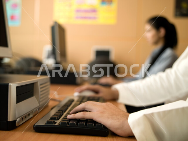 Integration and focus at work, academic schools in the Emirates, developed curricula and e-learning, practical application for students, teaching students how to use computer technologies, a close-up of an Emirati Arab student's hand typing on a keyboard