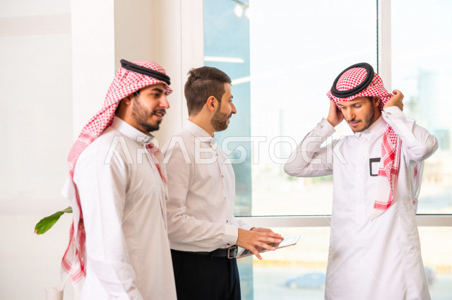 مجموعة من رجال الأعمال الرياديون الخليجيون ، احدهم من جنسية مختلفة يرتدي البدلة الرسمية ، ادارة الاعمال داخل مقر الشركة ، استخدام جهاز التابلت المحمول لاتمام المهام ، شركة سعودية ، بيئة العمل