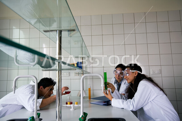 التجارب العلمية الحديثة وتطور طرق التعلم، مجموعة من الطلاب العربيين الخليجين الاماراتيين يرتدون نظارات الوقاية ويقومون بتجربة علمية كيميائية في مختبر الجامعة، الاستفادة والخبرة من التطبيق العملي في المخابر الكيميائية
