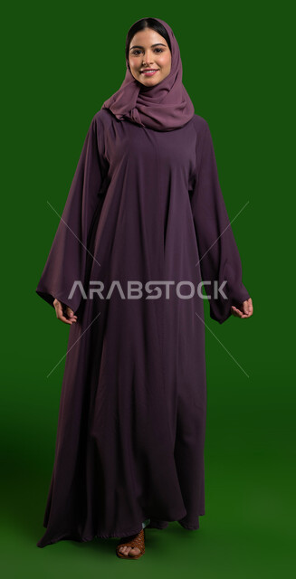 Gestures indicating happiness and joy Walking and moving forward with confidence, a portrait of a veiled Saudi Arab Gulf woman wearing a Saudi women's abaya with distinctive modern designs, the concept of fashion, elegance and beauty, green chroma backgro