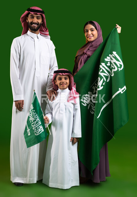 تعليم الأبناء تقدير وحب الوطن، التباهي بالإنتماء للمملكة، بورتريه لعائلة عربية خليجية سعودية سعيدة، الامساك بعلم السعودية بفخر، الاحتفال بيوم العلم 11 مارس، العيد الوطني السعودي 8 ربيع الأول، اليوم الوطني السعودي، صورة الجسم بالطول الكامل، كروما، خلفية خضراء