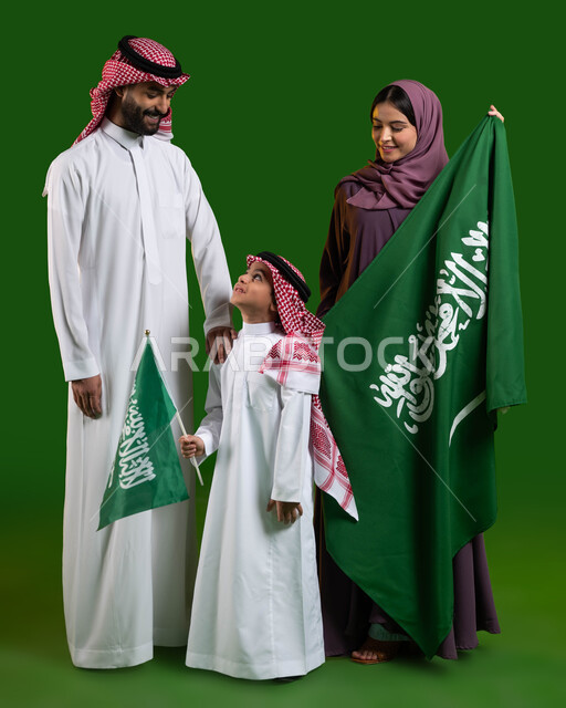 الترابط الأسري وحب الأبناء، بورتريه لاسرة عربية خليجية سعودية سعيدة، الامساك بعلم السعودية بحب وفخر، الاحتفال بيوم العلم 11 مارس، اليوم الوطني السعودي 23 سبتمبر، العيد الوطني السعودي، الولاء والانتماء للوطن، صورة الجسم بالطول الكامل، كروما، خلفية خضراء