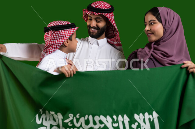 A Saudi family celebrating national occasions and holidays, the concept of a happy family, a portrait of a Saudi Gulf Arab family holding the Kingdom’s flag happily and proudly, the National Day for the Unification of Saudi Arabia, the Saudi National Day September 23, the Saudi Flag Day March 11, chroma, green background