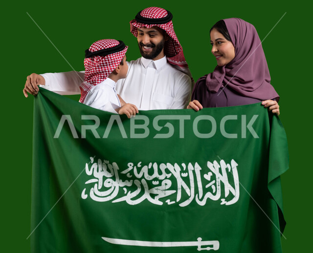 الاحتفال بالمناسبات والاعياد الوطنية مع الابناء، الترابط الاسري وحب العائلة، بورتريه لعائلة عربية خليجية سعودية تمسك علم المملكة بسعادة وفخر، اليوم الوطني لتوحيد السعودية، العيد الوطني السعودي 8 ربيع الاول، يوم العلم السعودي 11 مارس، كروما، خلفية خضراء