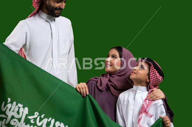 الانتماء والولاء للوطن، الترابط الاسري وحب العائلة، بورتريه لعائلة عربية خليجية سعودية تمسك علم المملكة بحب وفخر، الأعياد والمناسبات الوطنية السعودية، الاحتفال بيوم العلم السعودي 11 مارس، اليوم الوطني السعودي، العيد الوطني 8 ربيع الاول، كروما، خلفية خضراء