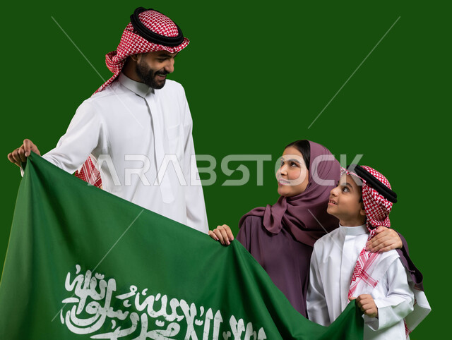 Pride in the nation’s identity, the concept of family cohesion, a portrait of a Saudi Gulf Arab family holding the Kingdom’s flag with love and pride, Saudi national holidays and events, celebration of the Saudi Flag Day, March 11, the Saudi National Day, the anniversary of the National Day, September 23, chroma, green background