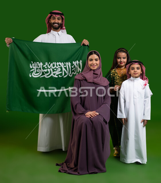 يوم العلم السعودي 11 مارس، بورتريه لعائلة عربية خليجية سعودية سعيدة، الإمساك بالعلم السعودي بحب وفخر، ارتداء الأزياء السعودية التقليدية الشعبية، اليوم الوطني 23 سبتمبر، الاحتفال مع العائلة بالعيد الوطني السعودي، صورة الجسم بالطول الكامل، كروما، خلفية خضراء