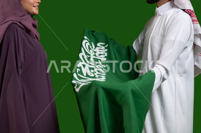 Pride and pride in the national identity, a close portrait of two Saudi Arabian Gulf citizens celebrating the Saudi Flag Day March 11, the anniversary of the National Day 8 Rabi` al-Awwal, the Saudi National Day, looks of love and tenderness, feelings of loyalty to the Kingdom, Saudi national events, chroma, green background