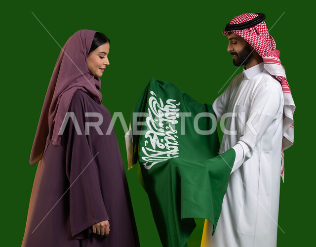 تعميق الانتماء والولاء للوطن، النظر الى علم السعودية بعز وافتخار، بورتريه لرجل وامرأة عربيان خليجيان سعوديان يحتفلان بالعيد الوطني 23 سبتمبر، اليوم الوطني السعودي، يوم العلم السعودي 11 مارس، المشاركة في المناسبات والأعياد الوطنية، كروما، خلفية خضراء