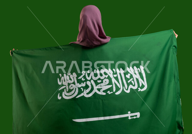 الإحتفال بالعيد الوطني السعودي، مفهوم الوفاء والإخلاص للمملكة، بورتريه من الخلف لسيدة عربية خليجية سعودية محجبة تضع علم السعودية على ظهرها، يوم العلم السعودي 11 مارس، ذكرى اليوم الوطني 8 ربيع الأول، الأعياد والمناسبات الوطنية السعودية، كروما، خلفية خضراء