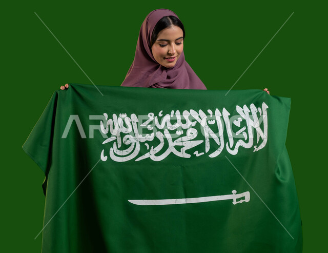 الفخر بإمتلاك الهوية السعودية، بورتريه لسيدة عربية خليجية سعودية محجبة تحمل علم المملكة بفخر وإعتزاز، الاحتفال باليوم الوطني لتوحيد السعودية 23 سبتمبر، يوم العلم السعودي 11 مارس، العيد الوطني السعودي، المناسبات والاعياد الوطنية، كروما، خلفية خضراء