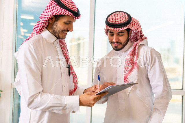 رجال اعمال سعوديين يتحدثون و يتناقشون في عقد العمل في مقر الشركة ، توقيع عقد عمل ،اتفاقية و صفقة جديدة ، شركاء عمل ، بيئة العمل