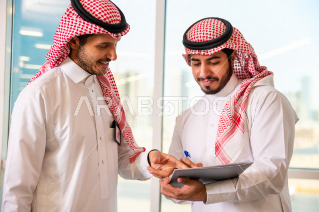 رجال اعمال سعوديين يتحدثون و يتناقشون في عقد العمل في مقر الشركة ، توقيع عقد عمل ،اتفاقية و صفقة جديدة ، شركاء عمل ، بيئة العمل