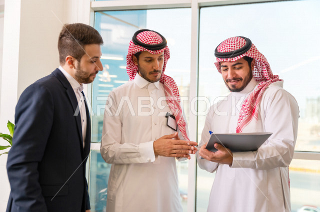 A group of Gulf entrepreneurial businessmen, one of whom is of different nationalities wearing a uniform, running a business inside the company's headquarters, a Saudi company, the work environment