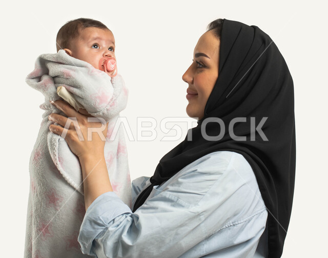 دور الأهل في تنميه مهارات الأولاد الحسيه والحركيه, بورتريه مقرب من الجانب لأم عربية خليجيه سعوديه ترتدي زي الكاجوال تنظر إلى طفلتها بإيماءات الحب, طفله حديثة الولاده تضع اللهايه, الاستمتاع بقضاء وقت ممتع مع الأطفال, خلفيه بيضاء