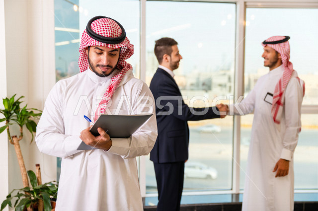A group of Gulf entrepreneurial businessmen, one of whom is of different nationalities wearing a uniform, running a business inside the company's headquarters, a Saudi company, the work environment