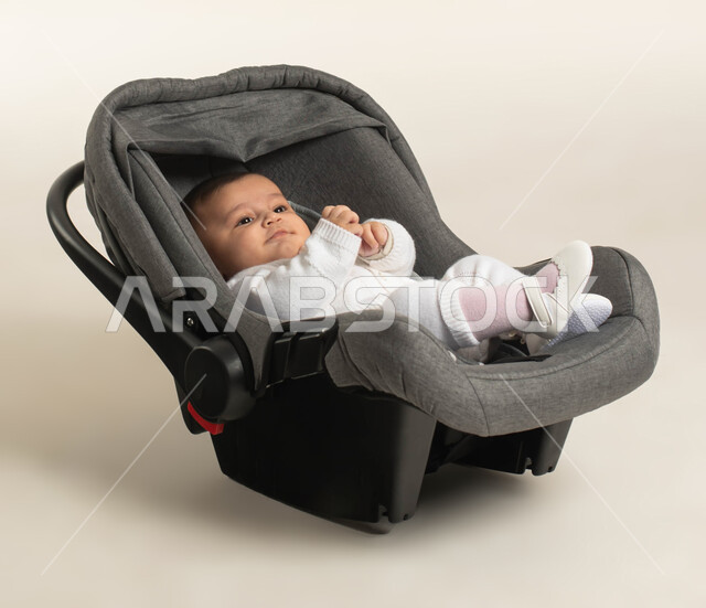 مفهوم النعومة و البراءة و الطفولة, ايماءات السعادة واللعب ,بورتريه لطفلة عربيه خليجيه سعودية لطيفة ترتدي لباس أبيض قطني تجلس في الكرسي الخاص بها , خلفية بيضاء