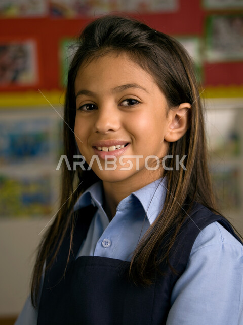 الاستعداد للعام الدراسي الجديد، التقاط صور شخصية للطلاب لتجهيز البطاقات التعريفية، صوره مقربة لفتاة عربية خليجية إماراتية ترتدي الزي المدرسي مبتسمة تنظر إلى الكاميرا، إيماءات وجه تدل السعادة بالعودة إلى المدرسة، المدارس الأكاديمية في الإمارات العربية.