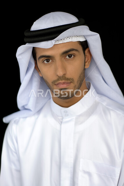 التقاط صورة شخصية للوثائق الرسمية, الاهتمام بالمظهر الخارجي, بورتريه مقرب لرجل عربي خليجي إماراتي يرتدي الكندورة والغترة ينظر إلى الكاميرا بإيماءت الجدية والثقة, خلفية سوداء