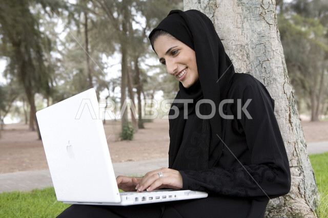 Completing work tasks, professionalizing computer and information technology jobs, a Saudi Arabian Gulf man using a laptop, using modern technical equipment, surfing the Internet, sitting outdoors, green nature, a remote work session
