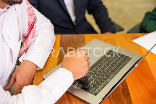 اجتماع اداري مع مجموعة من الأشخاص السعوديين الخليجيين في غرفة الاجتماعات  ، اجتماع رجال اعمال و سيده اعمال سويا داخل الشركة ، استخدام الكمبيوتر المحمول لادارة الاعمال ،  شركة سعودية ، عمل خليجي ،  فريق العمل 