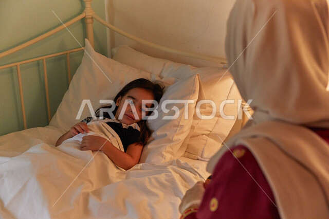 Commitment to drug treatment and the importance of using medication as a medical prescription. An Arab Gulf Emirati girl suffering from illness receives the appropriate drink from her mother. Regularity in taking medication at the correct time. The mother